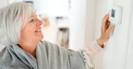 Grandma adjusting thermostat